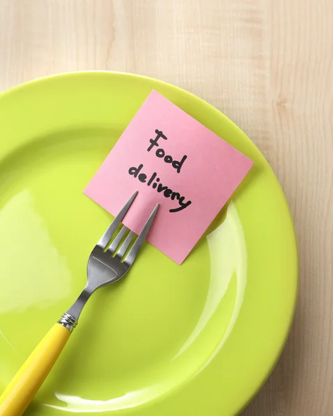 Note paper with message  attached to fork, on plate, on color wooden background — Stock Photo, Image