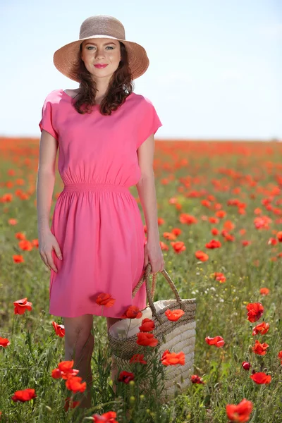 美しい若い女性にケシ畑で枝編み細工品の袋を保持 — ストック写真