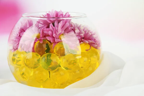 Vackra blommor i vas med hydrogel på bordet på ljus bakgrund — Stockfoto