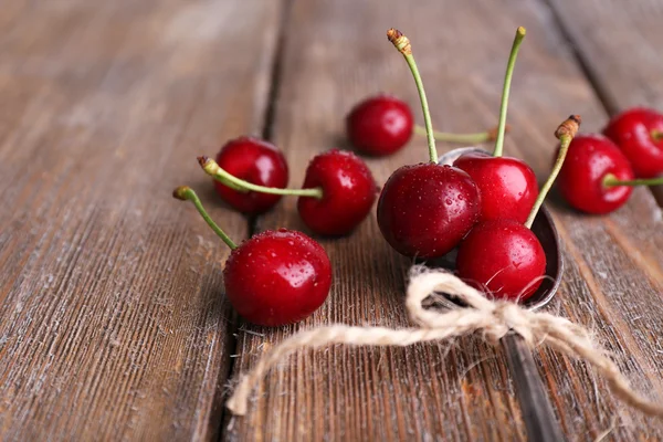 Ripe sweet cherries in spoon on wooden table — Stock Photo, Image