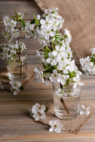 Schöne Obstblüte im Glas auf Tisch auf grauem Hintergrund — Stockfoto