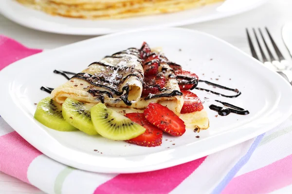 Delicious pancakes with strawberries and chocolate on plate on table — Stock Photo, Image