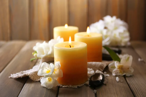 Hermosas velas con flores sobre fondo de madera — Foto de Stock