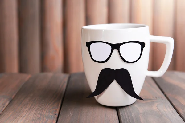 Cup with mustache on table on wooden background — Stock Photo, Image