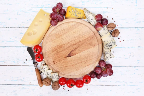 Different types of cheese with empty board on table close-up — Stock Photo, Image