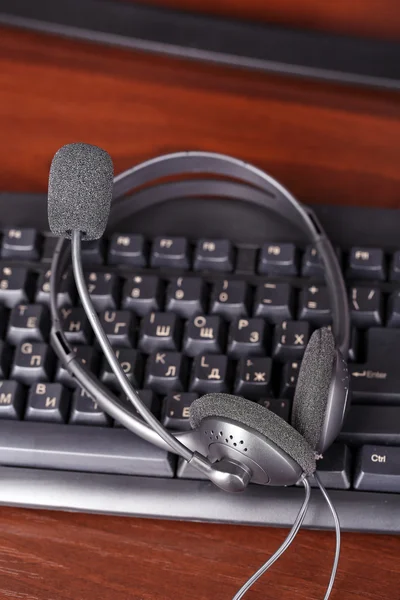 Headphone and keyboard close-up on wooden desk background — Stock Photo, Image
