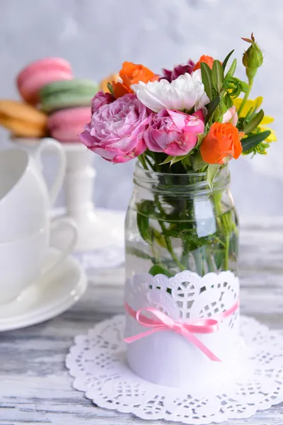 Hermoso ramo de flores brillantes en tarro sobre la mesa sobre fondo gris — Foto de Stock