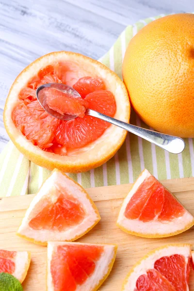 Ripe grapefruits on cutting board, on wooden table, on light background — Stock Photo, Image