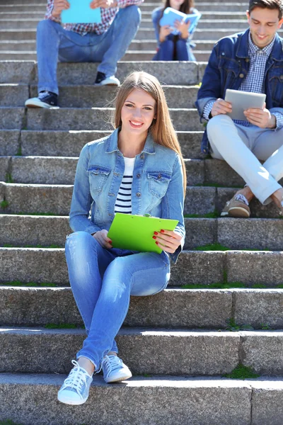 Šťastní studenti sedí na schodech v parku — Stock fotografie