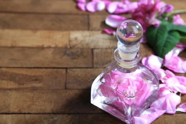 玫瑰精油，在瓶上彩色木背景 — 图库照片