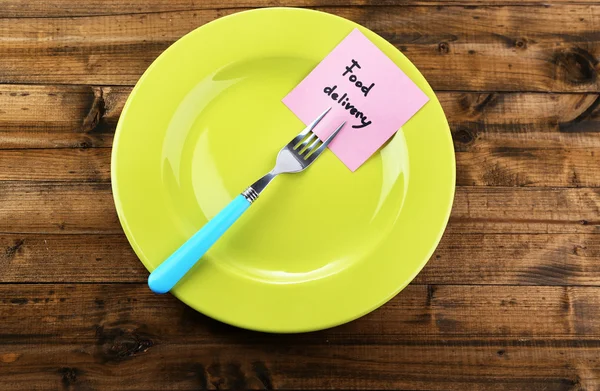 Note paper with message  attached to fork, on plate, on color wooden background — Stock Photo, Image