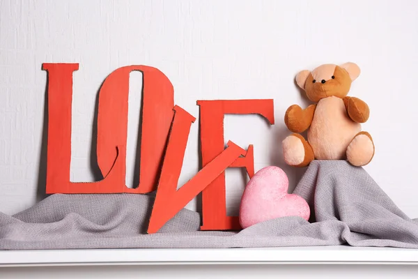 Letras decorativas formando palavra AMOR com ursinho de pelúcia no fundo da parede — Fotografia de Stock