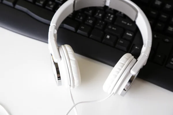 Headphone e teclado close-up no fundo da mesa branca — Fotografia de Stock