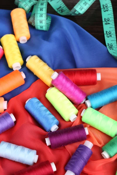 Hilos de costura multicolor sobre fondo de tela de color — Foto de Stock