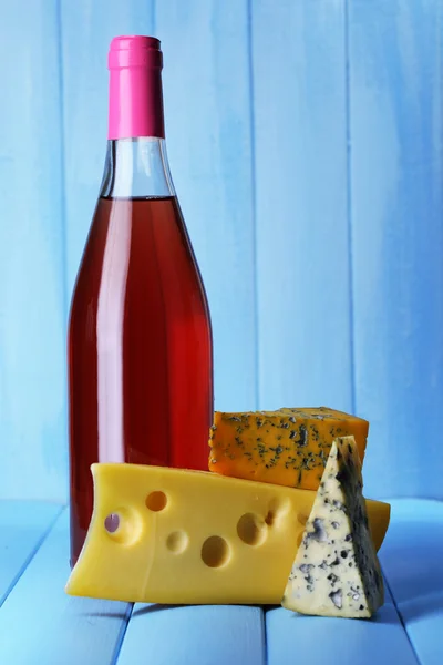 Vin rose et différents types de fromage sur fond en bois — Photo