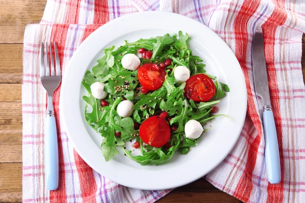 Roka, domates, peynir mozzarella toplar ve ahşap zemin üzerinde plaka üzerinde susam ile yapılan yeşil salata — Stok fotoğraf