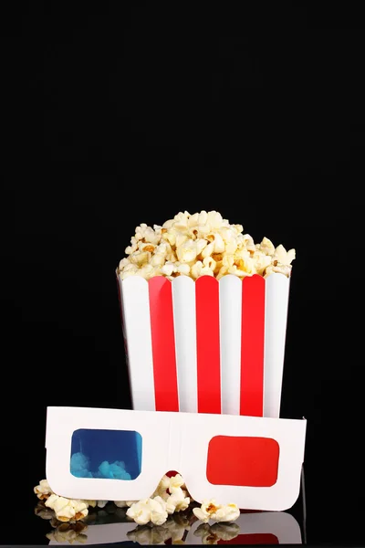 Popcorn en glazen geïsoleerd op zwart — Stockfoto