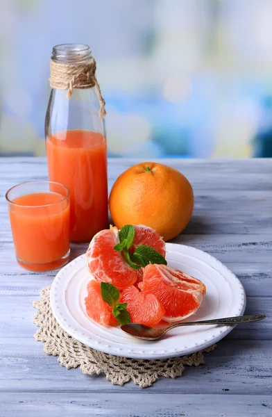 Reife geschälte Grapefruits auf Teller, auf farbigem Holztisch, auf hellem Hintergrund — Stockfoto