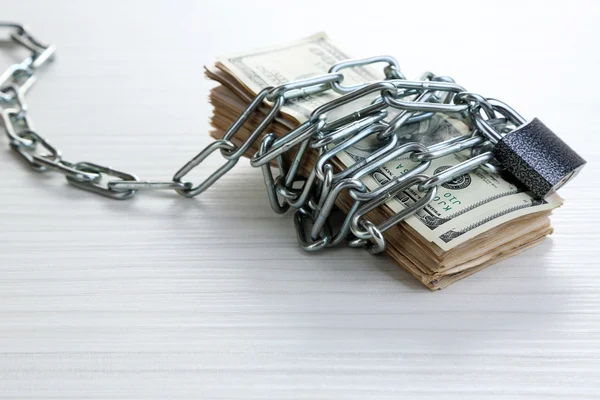 Dollars currency with lock and chain on wooden table — Stock Photo, Image