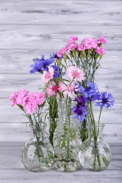 Vackra sommarblommor i vaser på grå trä bakgrund — Stockfoto