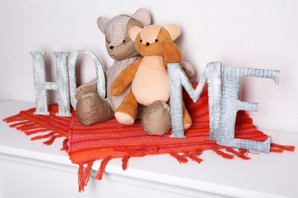 Letras decorativas formando palabra HOME con oso de peluche sobre fondo de pared — Foto de Stock