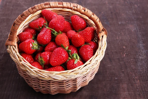 Maturare fragole dolci in cesto di vimini su sfondo di legno — Foto Stock