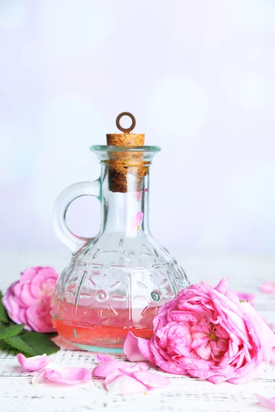 Huile de rose en bouteille sur table en bois de couleur, sur fond clair — Photo