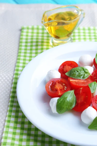 Ensalada Caprese con queso mozarella, tomates y albahaca en plato, sobre fondo de mesa de madera — Foto de Stock