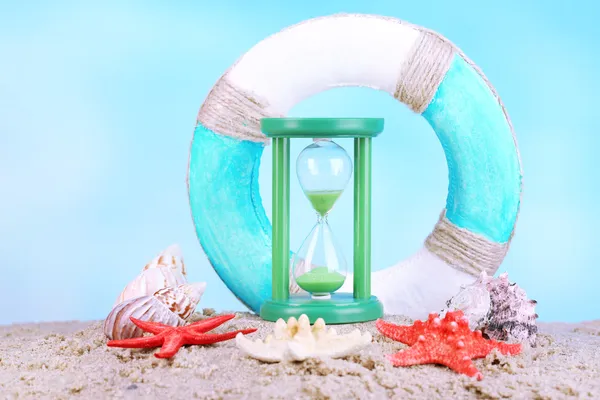 Hourglass in sand on blue sky background — Stock Photo, Image