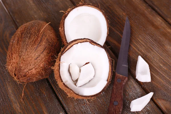 Coco quebrado com faca no fundo de madeira — Fotografia de Stock