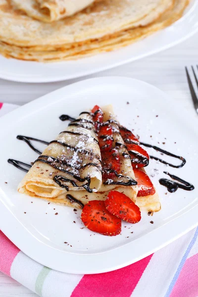 Delicioso panqueque con fresas y chocolate en plato en la mesa — Foto de Stock