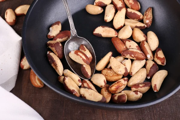 Tasty brasil nuts in pan on wooden background — Stock Photo, Image