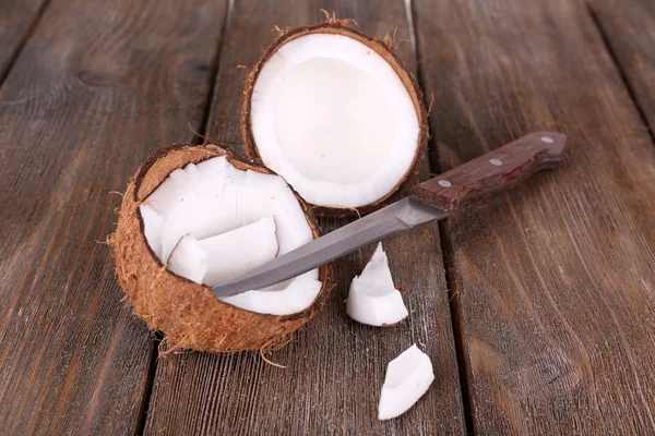 Coco quebrado com faca no fundo de madeira — Fotografia de Stock