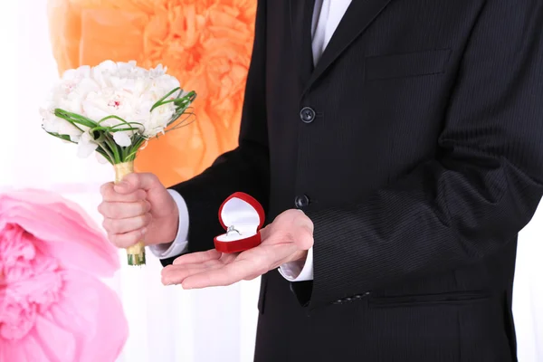 Hombre celebración de ramo de boda y anillo sobre fondo decorativo —  Fotos de Stock