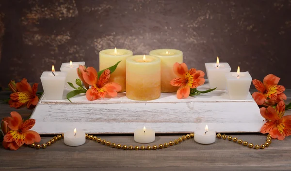 Belas velas com flores na mesa no fundo marrom — Fotografia de Stock