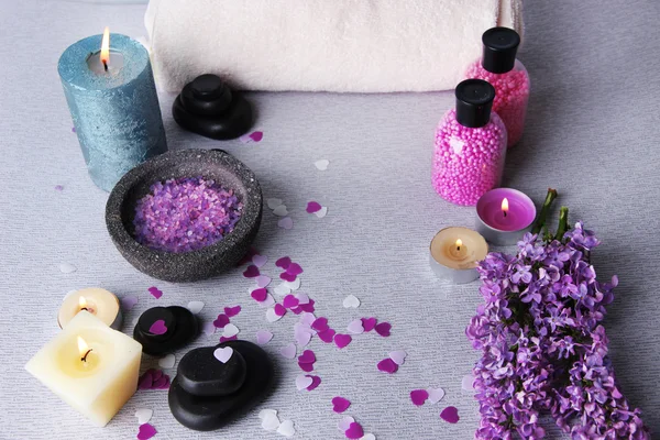 Samenstelling met spa behandeling, handdoeken en lila bloemen, op lichte achtergrond — Stockfoto