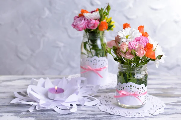 Beau bouquet de fleurs vives en pots sur table sur fond gris — Photo