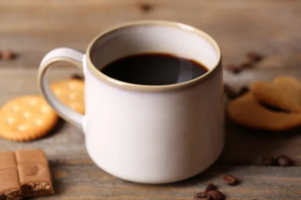 Cangkir dengan kopi panas dan kue manis, dengan latar belakang meja kayu — Stok Foto