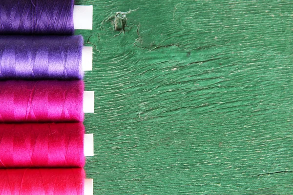 Linhas de costura multicoloridas em fundo de madeira — Fotografia de Stock