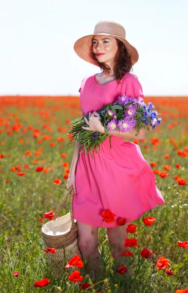 Hermosa mujer joven sosteniendo bolsa de mimbre en el campo de amapola —  Fotos de Stock