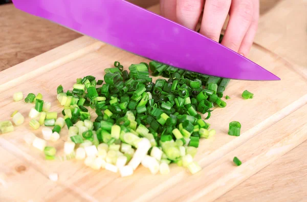 Female hand cutting chives on cutting board — Stock Photo, Image