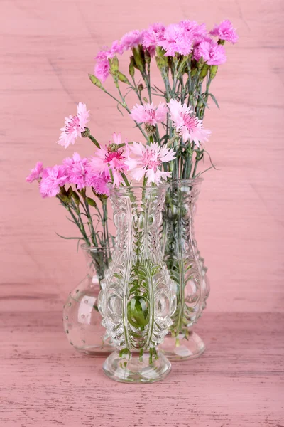 Belles fleurs d'été dans des vases sur fond de bois rose — Photo