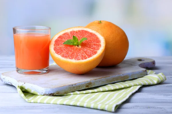 Ripe grapefruits and fresh juice on cutting board, on wooden background — Stock Photo, Image