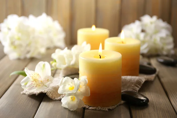 Beautiful candles with flowers on wooden background Stock Picture