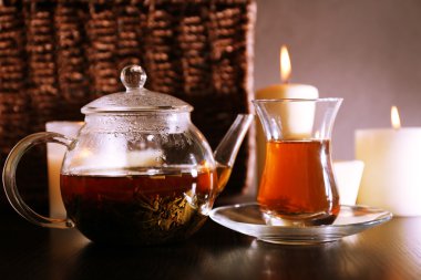 Çay cam çaydanlık ve tablo, koyu arka plan üzerinde mum ile kompozisyon