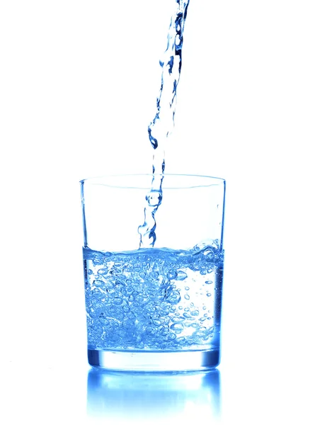 Menuang air ke kaca di latar belakang biru — Stok Foto