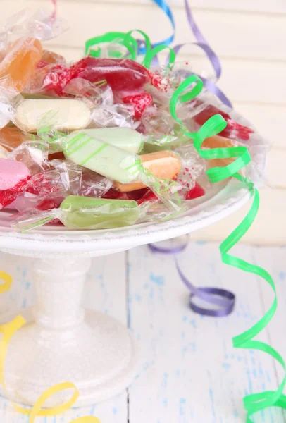 Tasty candies on plate on table on wooden background — Stock Photo, Image