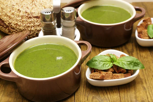 Tasty soup in saucepans on wooden table, close up — Stock Photo, Image