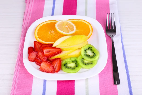 Различные нарезанные фрукты на тарелке на салфетке крупным планом — стоковое фото