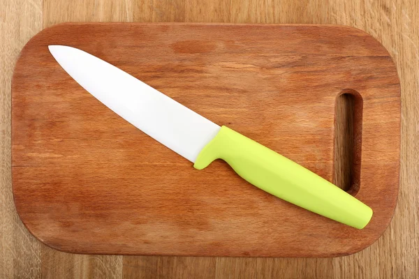 Kitchen knife and cutting board on wooden table — Stock Photo, Image